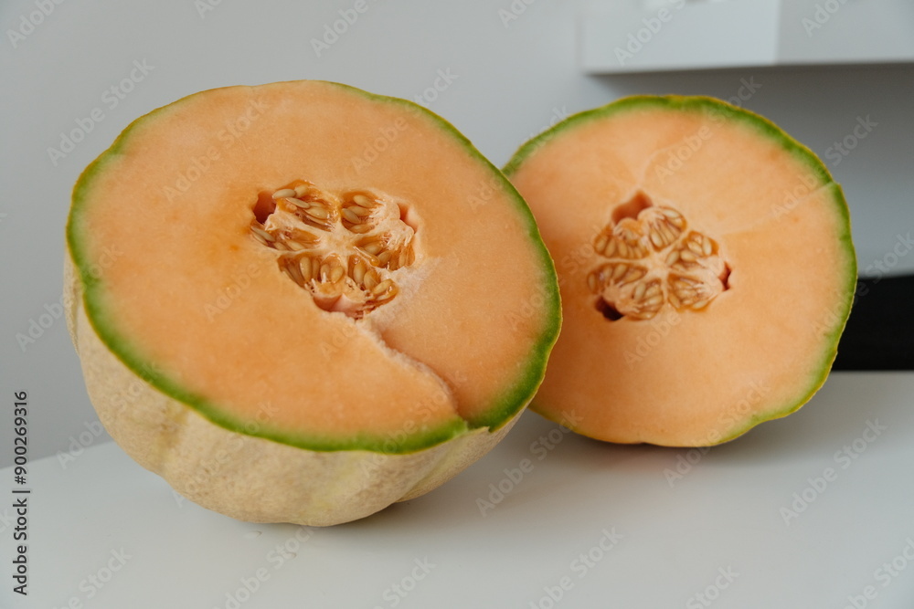 Close-up of two halved cantaloupe melons showcasing the seeds and orange flesh, highlighting their freshness and vibrant color Close-up of two halved cantaloupe melons showcasing the seeds and orange flesh, highlighting their freshness and vibrant color