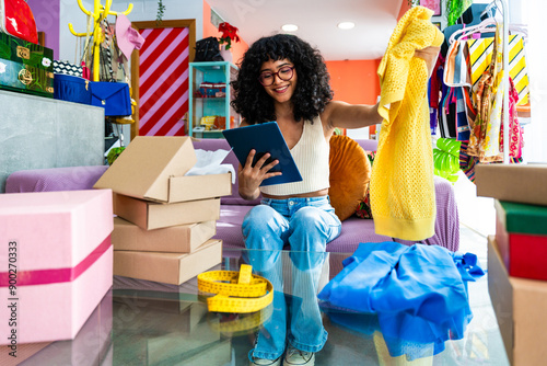 Beautiful young hispanic woman managing her home clothing e-commerce business from home - Female designer  owns online shopping store, concepts of home business and reselling second hand accessories  photo