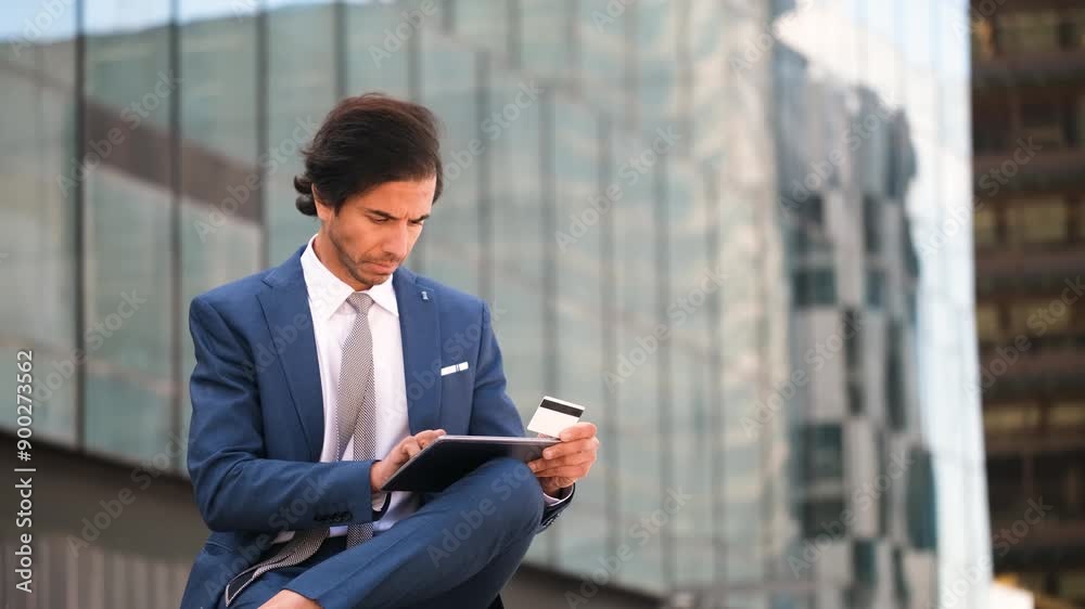 Indian businessman in a suit making a purchase with credit card and a tablet. Concept of shopping online Indian businessman in a suit making a purchase with credit card and a tablet. Concept of shopping online