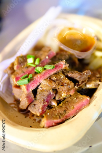 Grilled steak sliced on a plate with blurred background.