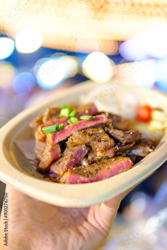Grilled steak sliced on a plate with blurred background.