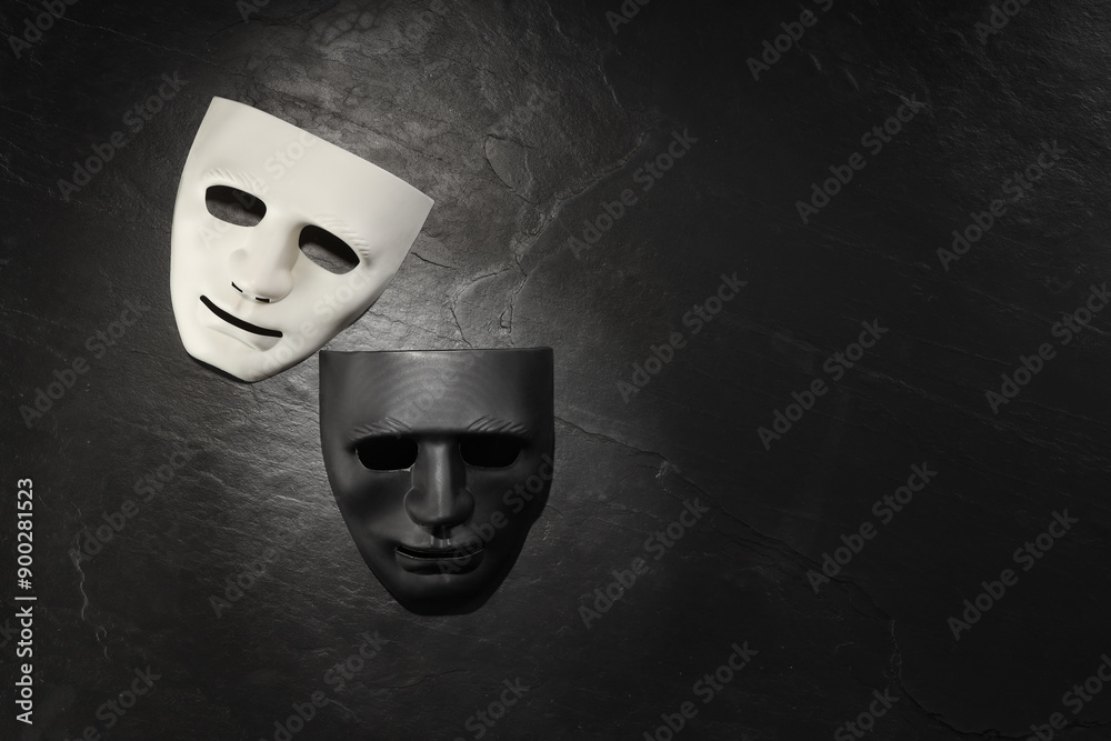 Plastic face masks on black slate surface, top view and space for text. Theatrical performance Plastic face masks on black slate surface, top view and space for text. Theatrical performance