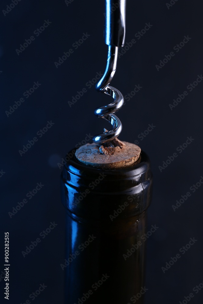 Wine bottle with corkscrew on dark background, closeup Wine bottle with corkscrew on dark background, closeup