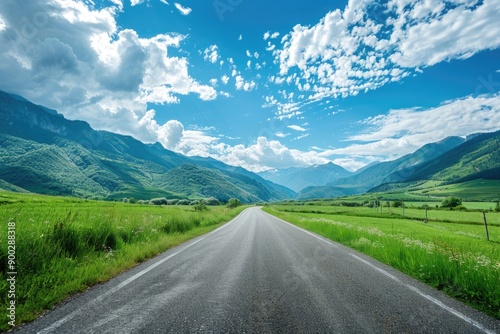 A scenic landscape of a long empty road stretching out to the horizon with distant mountains in the background