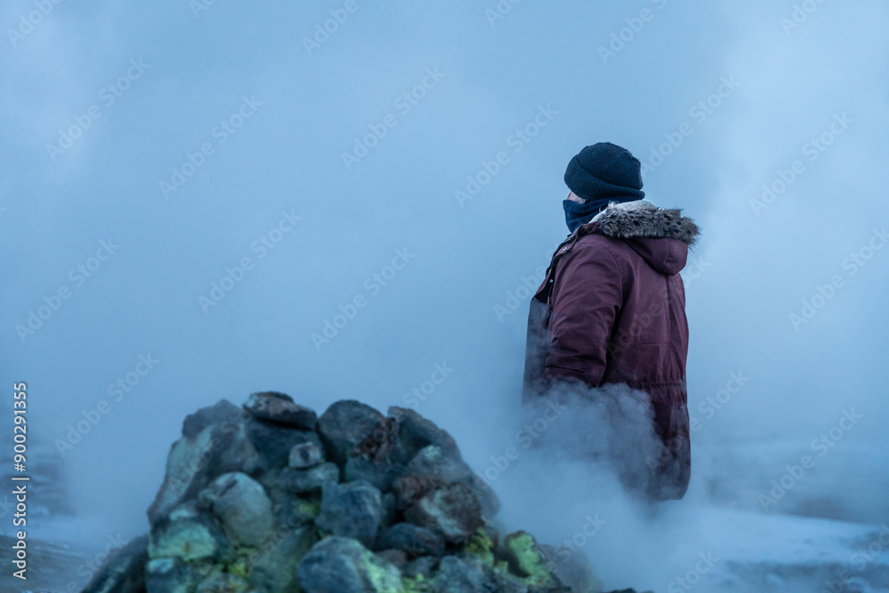 A man walking behind the steaming fumaroles at Hverir or Namafjall geothermal park in winter, Iceland A man walking behind the steaming fumaroles at Hverir or Namafjall geothermal park in winter, Iceland