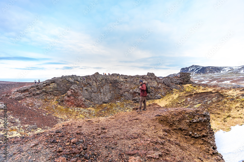 A hiker with a backpack in the Saxholl Crater volcano crater in winter in Iceland, Snaefellsnes Peninsula A hiker with a backpack in the Saxholl Crater volcano crater in winter in Iceland, Snaefellsnes Peninsula