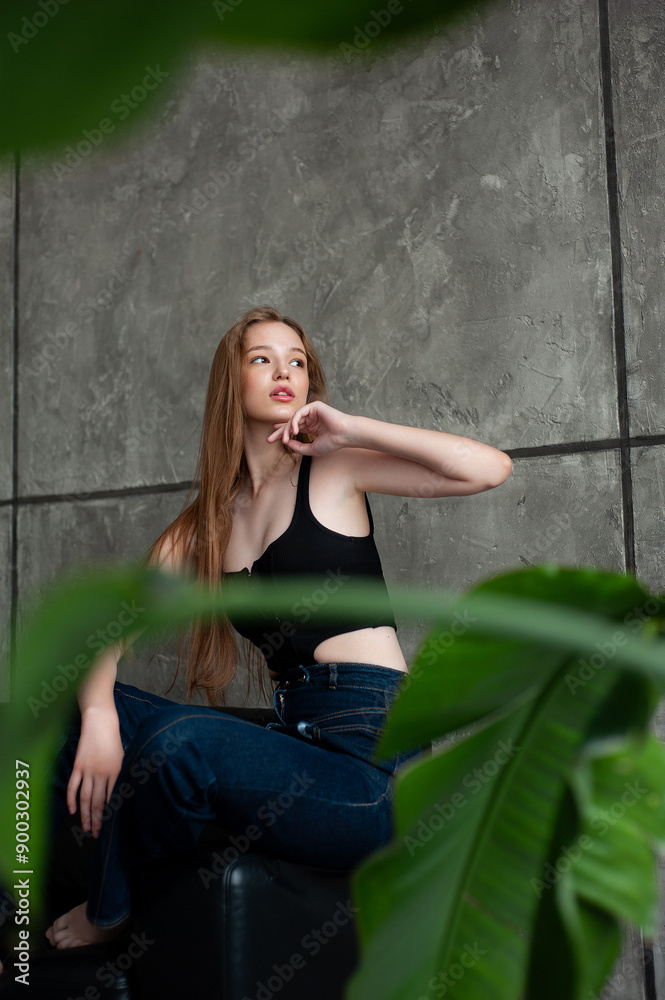 Fototapeta premium Modern female in casual clothes keeping hand in hair and smiling while sitting on the sofa