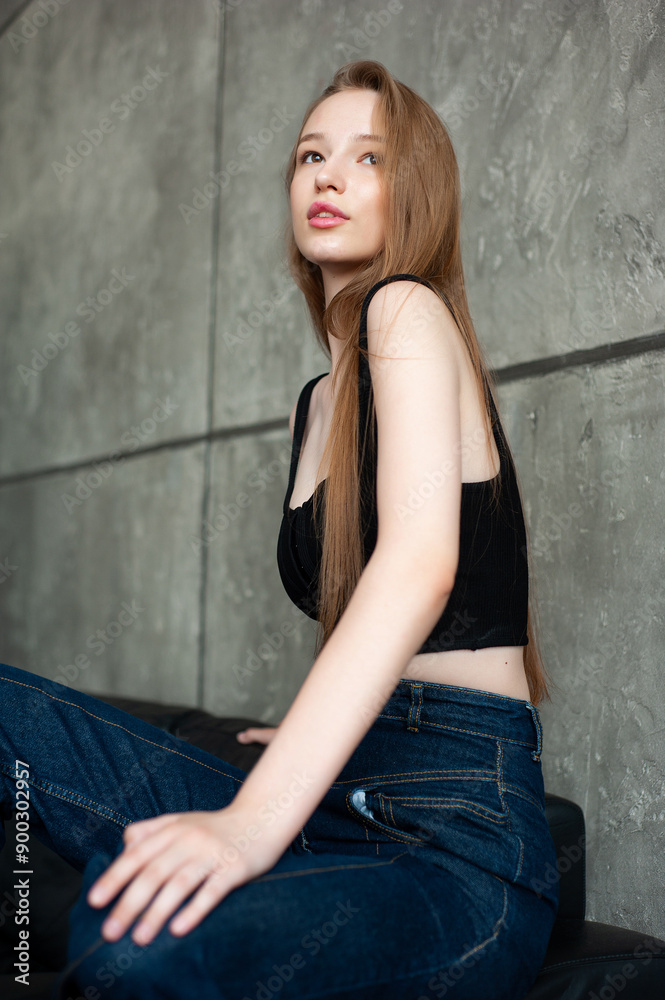 Modern female in casual clothes keeping hand in hair and smiling while sitting on the sofa Modern female in casual clothes keeping hand in hair and smiling while sitting on the sofa