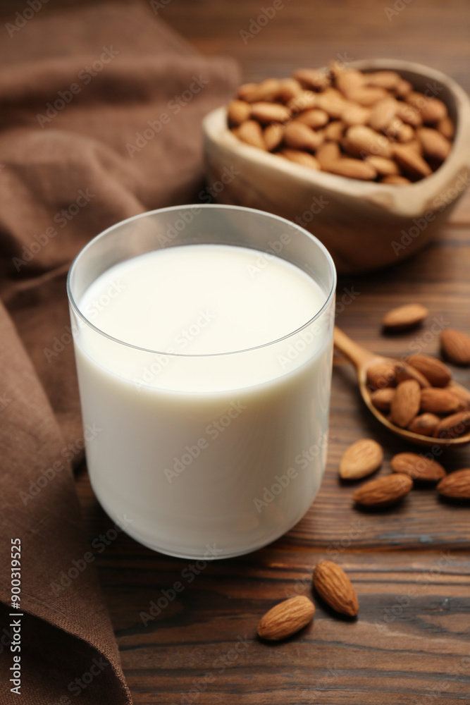 Glass of almond milk and almonds on wooden table Glass of almond milk and almonds on wooden table