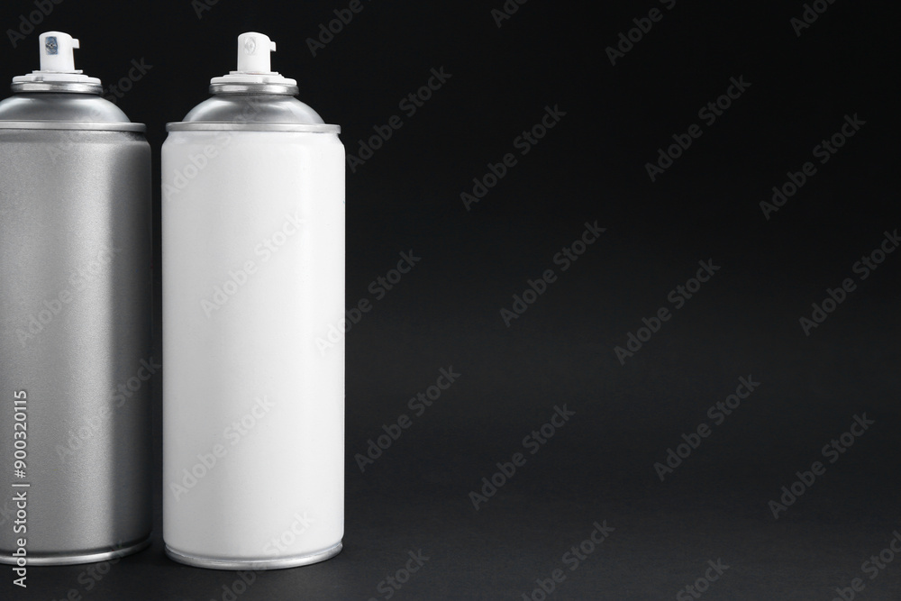 Two spray paint cans on dark gray background, space for text Two spray paint cans on dark gray background, space for text