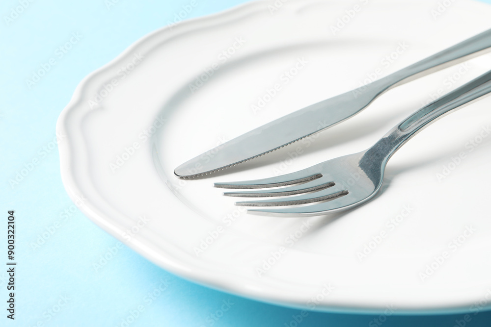 Stylish silver cutlery and plate on light blue background, closeup Stylish silver cutlery and plate on light blue background, closeup