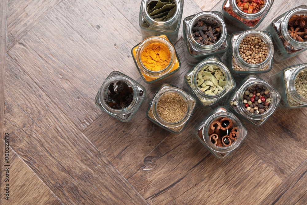 Different spices in glass jars on wooden table, flat lay. Space for text Different spices in glass jars on wooden table, flat lay. Space for text
