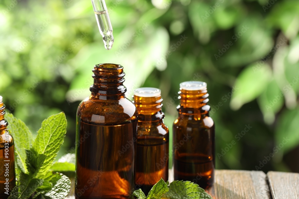 Essential oil dripping from pipette into bottle on table, closeup. Space for text Essential oil dripping from pipette into bottle on table, closeup. Space for text