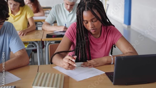 African American Girl writing essay test at college classroom - High school teenager students taking exam