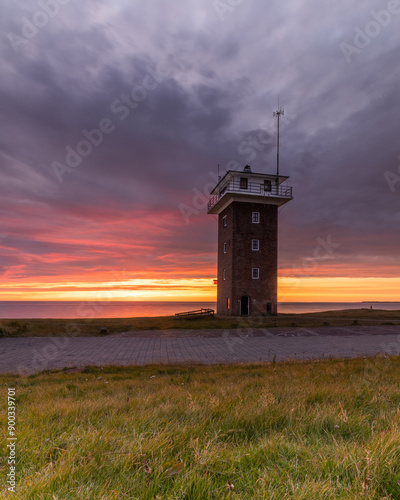 The little tower of Den Helder on the North Sea coast under a colorful evening sky. Formerly a coast guard tower, it is now available for rent as a holiday home.