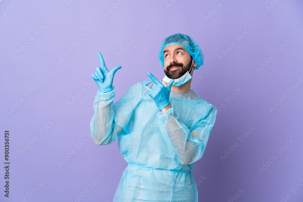 Surgeon man with beard with blue uniform over isolated purple background pointing with the index finger a great idea Surgeon man with beard with blue uniform over isolated purple background pointing with the index finger a great idea