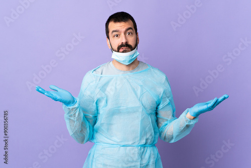 Surgeon man with beard with blue uniform over isolated purple background having doubts while raising hands