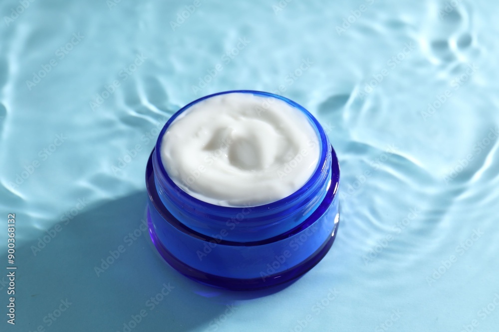 Jar with face cream in water on light blue background Jar with face cream in water on light blue background