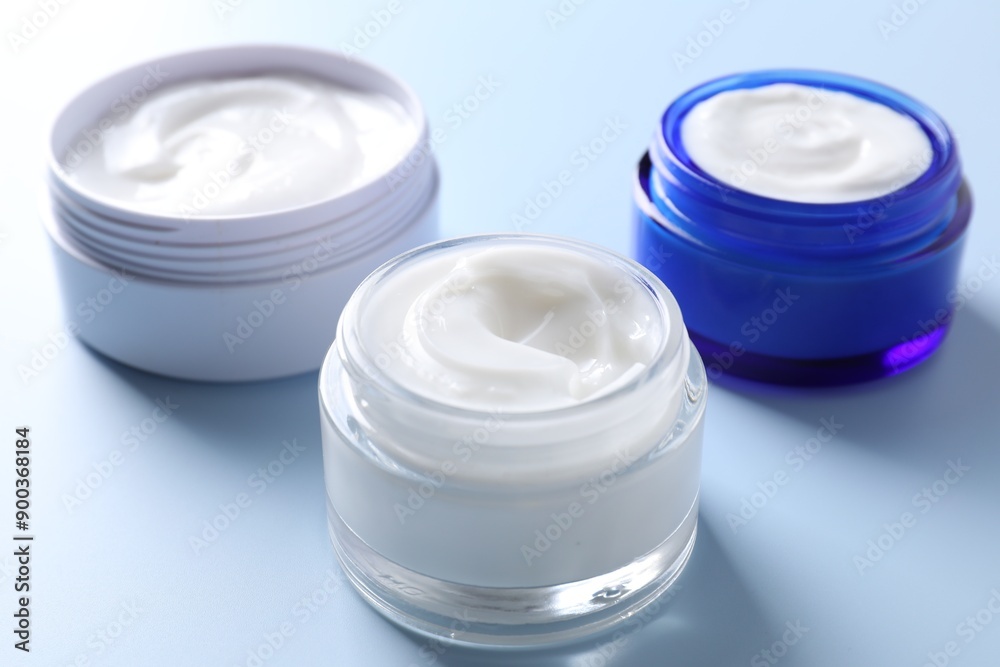 Face cream in jars on light blue background, closeup Face cream in jars on light blue background, closeup