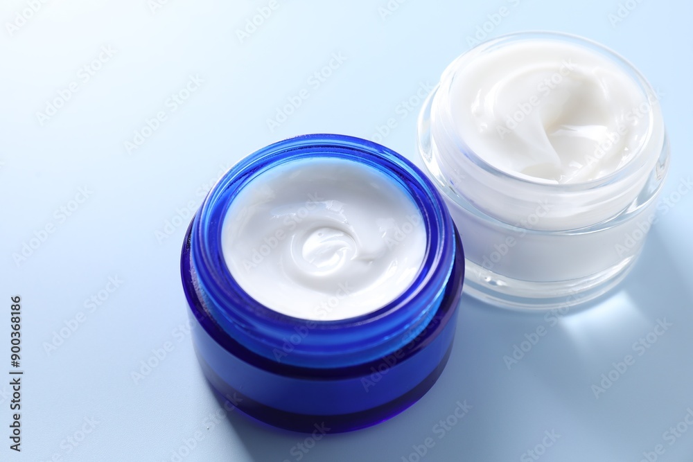 Face cream in jars on light blue background, closeup Face cream in jars on light blue background, closeup