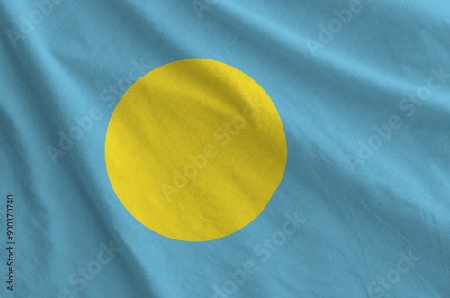 Palau flag depicted on folded wavy fabric of old cloth close up photo