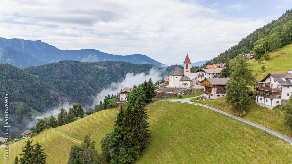 Aerial drone view of village, town Eores (Afers) near Bressanone (Brixen). Cloudy summer day. View on the Church of San Giorgio in the centre. Idyllic mountain village in the Italian Dolomites. Aerial drone view of village, town Eores (Afers) near Bressanone (Brixen). Cloudy summer day. View on the Church of San Giorgio in the centre. Idyllic mountain village in the Italian Dolomites.