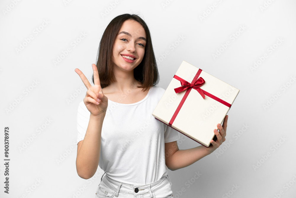 Young Ukrainian woman holding a gift isolated on white background smiling and showing victory sign Young Ukrainian woman holding a gift isolated on white background smiling and showing victory sign