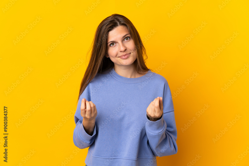 Young Slovak woman isolated on yellow background making money gesture but is ruined Young Slovak woman isolated on yellow background making money gesture but is ruined