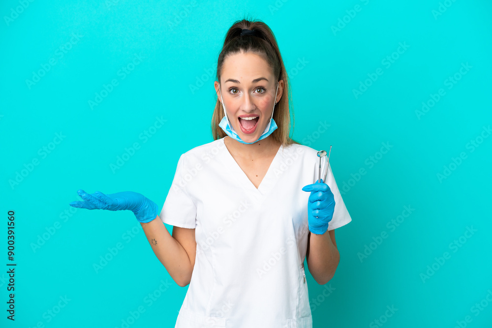 Dentist caucasian woman holding tools isolated on blue background with shocked facial expression Dentist caucasian woman holding tools isolated on blue background with shocked facial expression