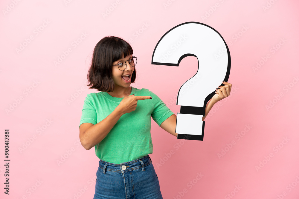 Youing woman holding a question mark icon with surprised expression Youing woman holding a question mark icon with surprised expression