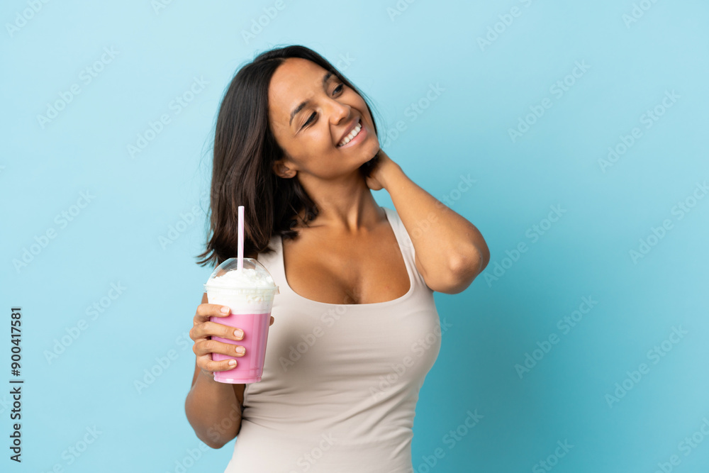 Young woman with strawberry milkshake isolated on blue background thinking an idea Young woman with strawberry milkshake isolated on blue background thinking an idea