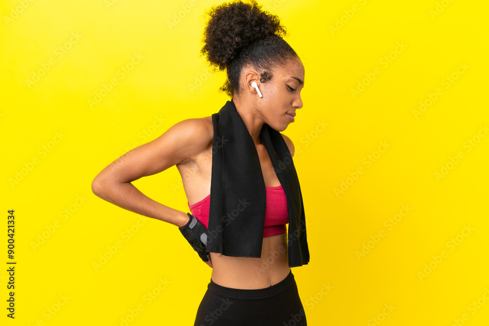 Young African sport woman isolated on yellow background suffering from backache for having made an effort Young African sport woman isolated on yellow background suffering from backache for having made an effort