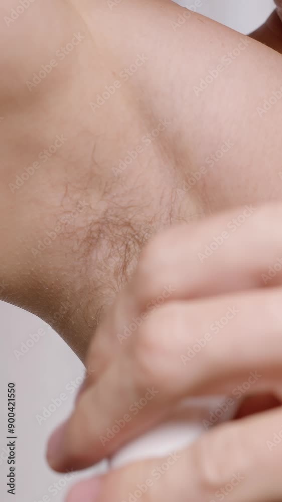 Vertical video. Maintaining fresh underarms throughout the day a crucial step in any morning routine. Here, a man applies deodorant in a well-lit bathroom. Vertical video. Maintaining fresh underarms throughout the day a crucial step in any morning routine. Here, a man applies deodorant in a well-lit bathroom.