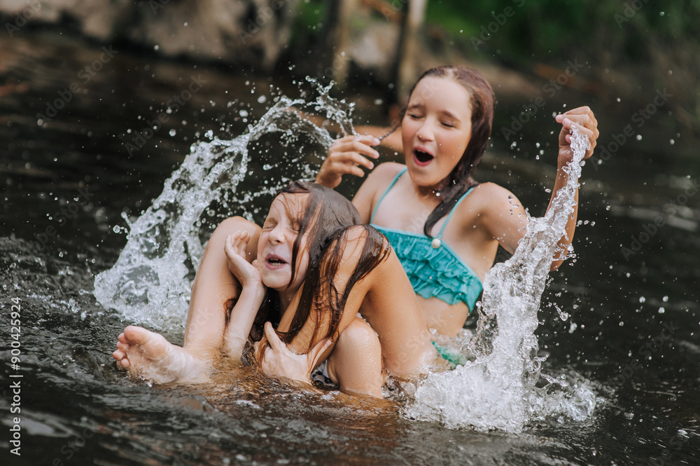 Obraz premium Two happy girlfriends, smiling children in water playing, laughing, having fun in the lake in summer, swimming in the sea on vacation. Photography, close-up portrait, childhood concept.