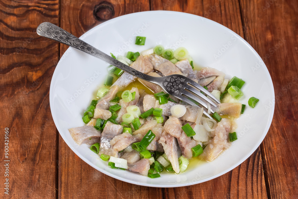 Sliced pickled herring with green onion and fork on dish
Sliced pickled herring with green onion and fork on dish