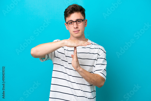 Young handsome Brazilian man isolated on blue background making time out gesture photo