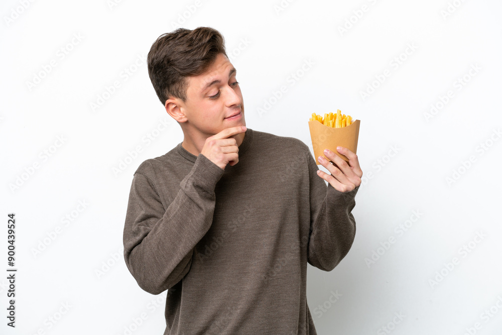 Young Brazilian man holding fried chips isolated on white background and looking up Young Brazilian man holding fried chips isolated on white background and looking up