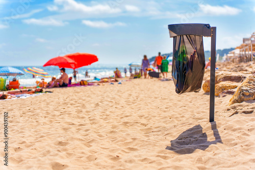 Black Trash Bin Near Beachgoers on Sunny Day photo