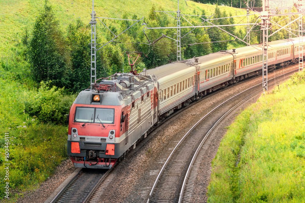 Naklejka premium Passenger train moving gracefully along a scenic curved track in a beautiful countryside