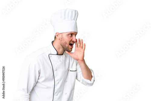 Young caucasian chef over isolated chroma key background shouting with mouth wide open to the lateral photo