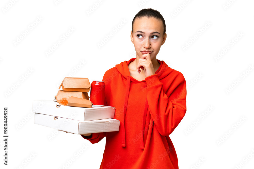 Young Arab woman holding fast food over isolated background and looking up Young Arab woman holding fast food over isolated background and looking up