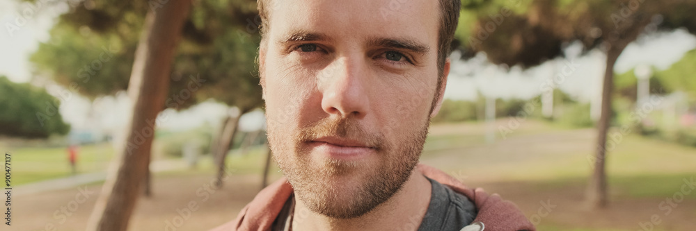 Obraz premium Close up, young man turns his head, looks at the camera and smiles, panorama