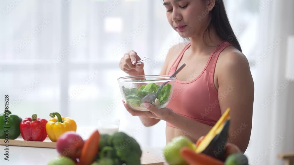 Healthy eating: young woman savoring green salad in stylish kitchen Healthy eating: young woman savoring green salad in stylish kitchen
