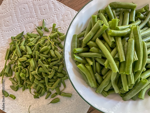 Fresh snipped green beans in a bowl with the tips on a paper towel photo