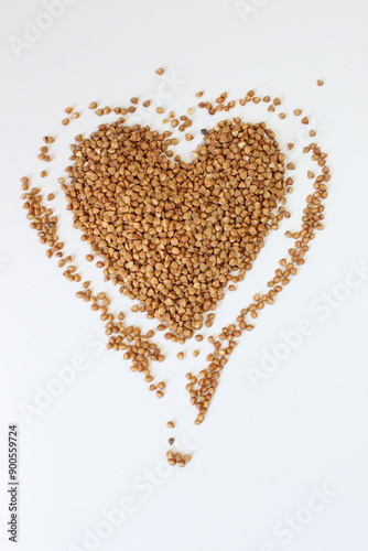 Buckwheat is forming a heart shape on a white background representing the concept of healthy eating