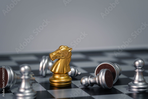 Golden chess knight standing out among toppled silver pieces on a checkered board, symbolizing victory, strategy, and leadership.