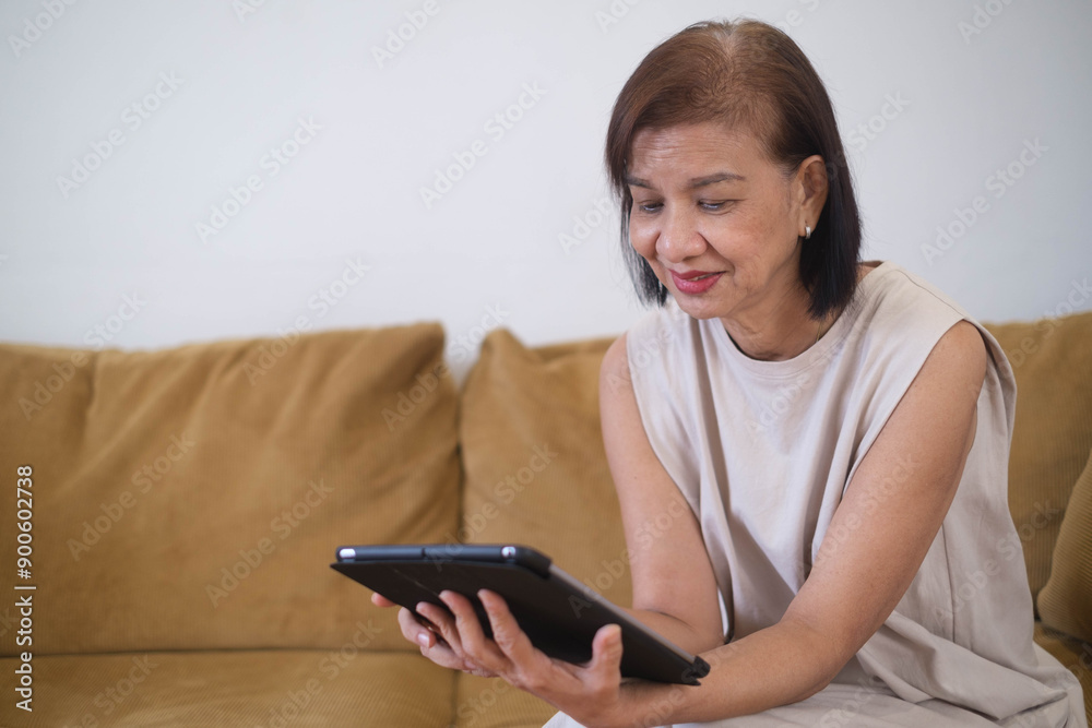 Woman sitting on a yellow couch, smiling while using a digital tablet. Modern technology and casual home setting, relaxed lifestyle. Woman sitting on a yellow couch, smiling while using a digital tablet. Modern technology and casual home setting, relaxed lifestyle.