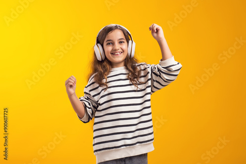 Smiling kid girl enjoying music in headphones on yellow background. Lifestyle and leasure concept photo