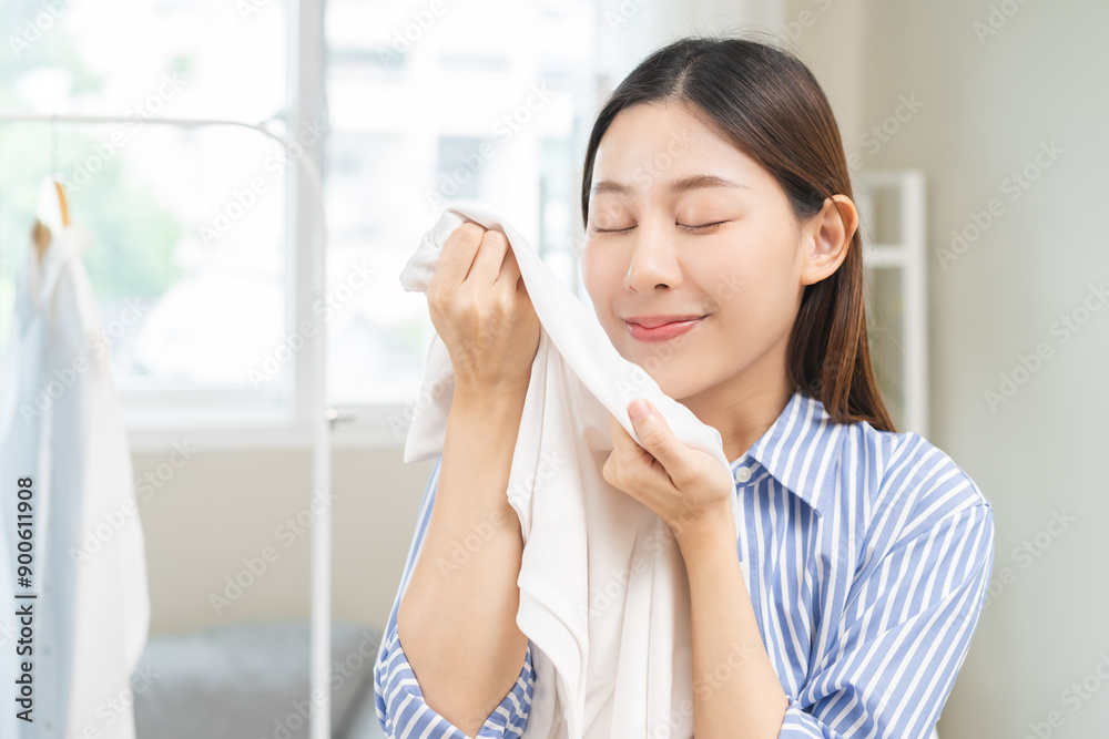Feel softness, hygiene. Smile asian young woman touching fluffy white shirt smelling fresh clean clothes, pretty girl comfort sniff after washing laundry. Household work at home, chore of maid concept Feel softness, hygiene. Smile asian young woman touching fluffy white shirt smelling fresh clean clothes, pretty girl comfort sniff after washing laundry. Household work at home, chore of maid concept