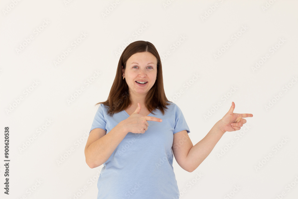 Hey look. Smiling pretty female model pointing fingers right at empty space and inviting to check it out, showing advertisement on white background. Hey look. Smiling pretty female model pointing fingers right at empty space and inviting to check it out, showing advertisement on white background.